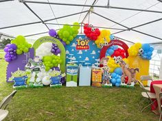 an outdoor birthday party with balloons and decorations on the grass in front of a tent