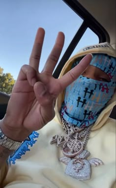 a person in a car wearing a face mask and making the peace sign with their hand