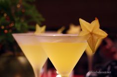 two glasses filled with drinks sitting on top of a table next to a christmas tree