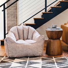 a living room with two chairs and a stair case in the background, along with a rug on the floor