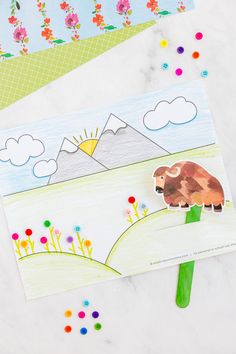 the paper is cut out to look like a cow on top of a hill with flowers