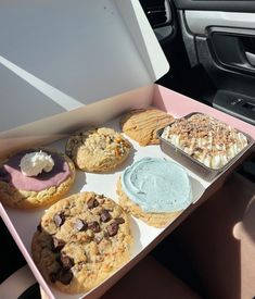 an open box filled with different types of cookies and ice cream on top of a car seat