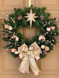 a christmas wreath hanging on the front door with ornaments around it and a star above