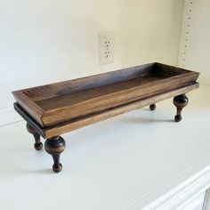 a wooden tray sitting on top of a white counter next to a light switch box