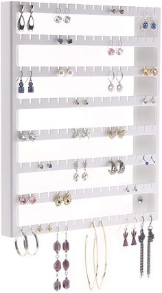 a white wall mounted jewelry rack with earrings