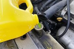 a yellow plastic container filled with water next to a car's fuel tank and hose