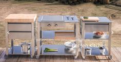 three stainless steel outdoor cooking carts on a wooden deck with mountains in the back ground