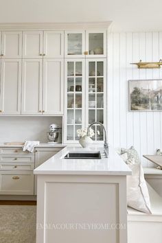 a kitchen with white cabinets and counter tops