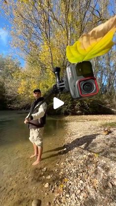 a man standing in the water with a camera attached to his chest and holding a fishing rod