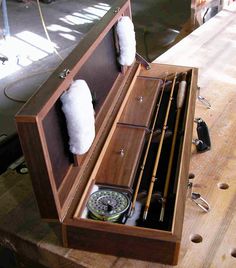 an open wooden box with two pairs of fishing rods in it on top of a table