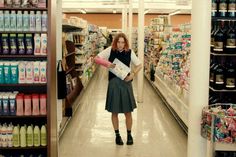 a woman is standing in the aisle of a grocery store with her arm wrapped around an item