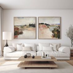 two paintings hang on the wall above a white couch and coffee table in a living room