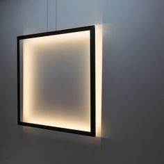 a square light fixture hanging from the side of a wall next to a white wall