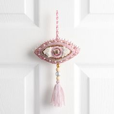 an eye shaped decoration hangs on the front door with beads and tassels hanging from it