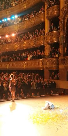 a woman standing on top of a stage in front of an auditorium filled with people