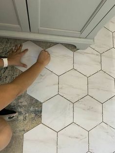 a person is using a sponge to clean a marble tile floor with a cloth on it