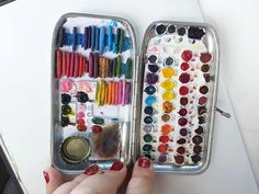 a person holding an open tin with lots of paint and crayons in it