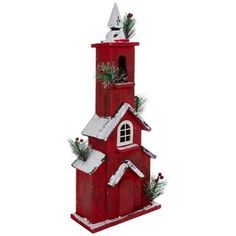 a red birdhouse with snow on the roof and trees in the top, is shown