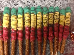 there are many decorated cookies in the shape of people's faces on sticks with different colors