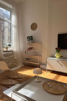 a living room filled with furniture and a large window next to a white table topped with a lamp