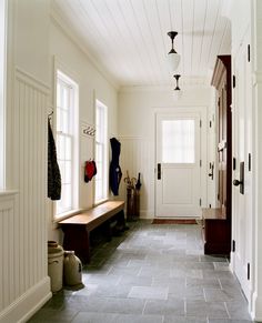 an image of a hallway with white walls and wood trim on the door, windows, and bench