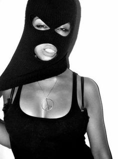 a woman wearing a black mask and holding a cell phone to her face with one hand