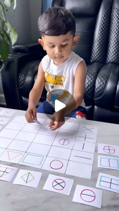 a little boy sitting at a table with some cut outs