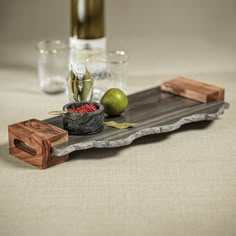 a tray with some fruit on it next to a wine bottle and glass vases