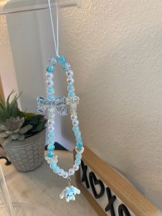 a cross hanging from the side of a wooden shelf next to a potted plant