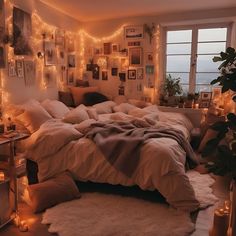 an unmade bed in a bedroom with lights on the wall and pictures above it