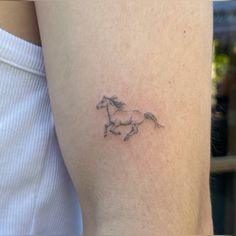 a small tattoo of a running horse on the left thigh, with an arrow in the middle