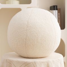 a large white ball sitting on top of a table next to a book shelf and mirror