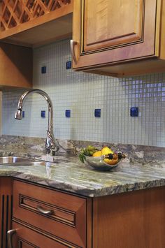 a bowl of fruit sitting on top of a kitchen counter next to a faucet