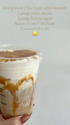 someone holding up a cup of coffee with whipped cream and caramel