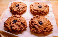 four oatmeal cookies sitting on top of a piece of parchment paper