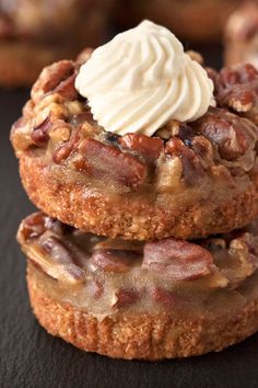 two cookies covered in icing and pecans on top of a black tablecloth