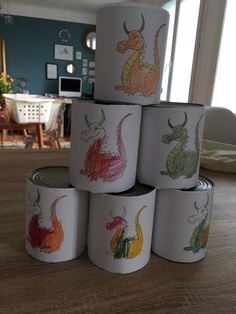 six cups with drawings on them sitting on a table in front of a couch and dining room