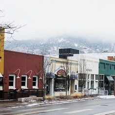 a row of buildings sitting on the side of a road next to snow covered mountains