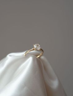 a diamond ring sitting on top of a white satin material covered pillow with the fabric draped around it