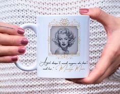 a woman's hand holding a coffee mug with an image of marilyn monroe on it