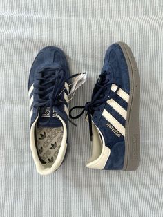 a pair of blue adidas sneakers sitting on top of a white bed sheet covered floor