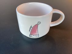 a white coffee cup with a pink hat on it