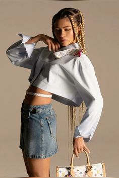 a woman with braids holding a purse and posing for the camera, in front of a white background