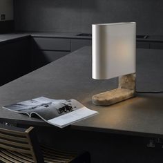 a table lamp sitting on top of a desk next to an open book and magazine