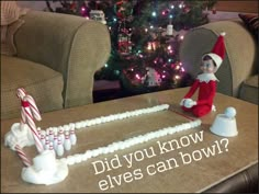 an elf sitting on top of a table next to candy canes