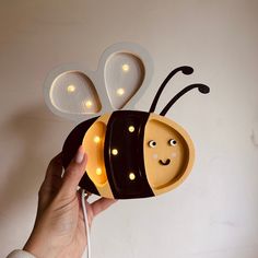 a hand is holding a light up bee