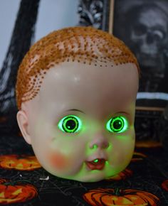 a creepy doll with glowing green eyes sitting on a table