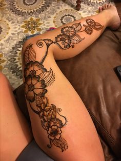 a woman laying on top of a brown couch next to a remote control covered in hendi tattoos