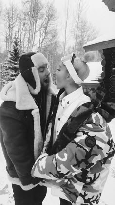 black and white photograph of two people in the snow, one is kissing the other