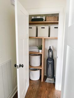 an open closet with several storage containers and a vacuum